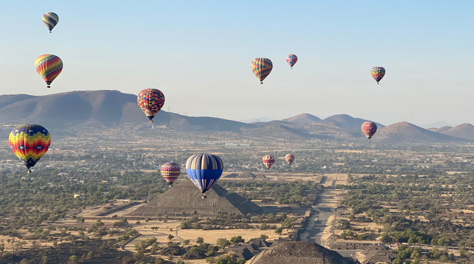 Twelve colourful hot air balloons float in the air above the Teotihuacán pyramids in Mexico